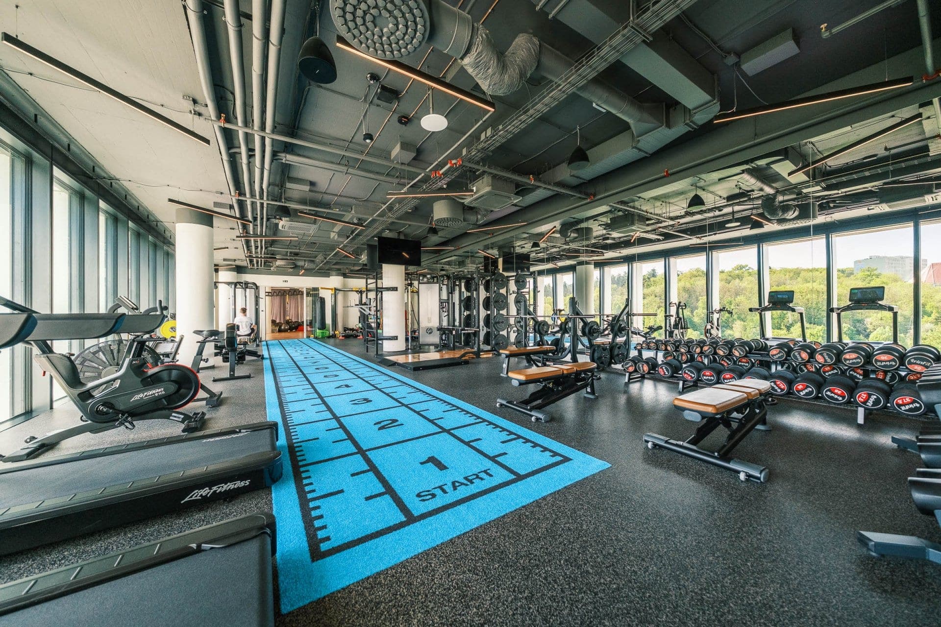 Firemní fitness SCS Software: běžecká dráha, kardio a volné váhy u prosklené fasády