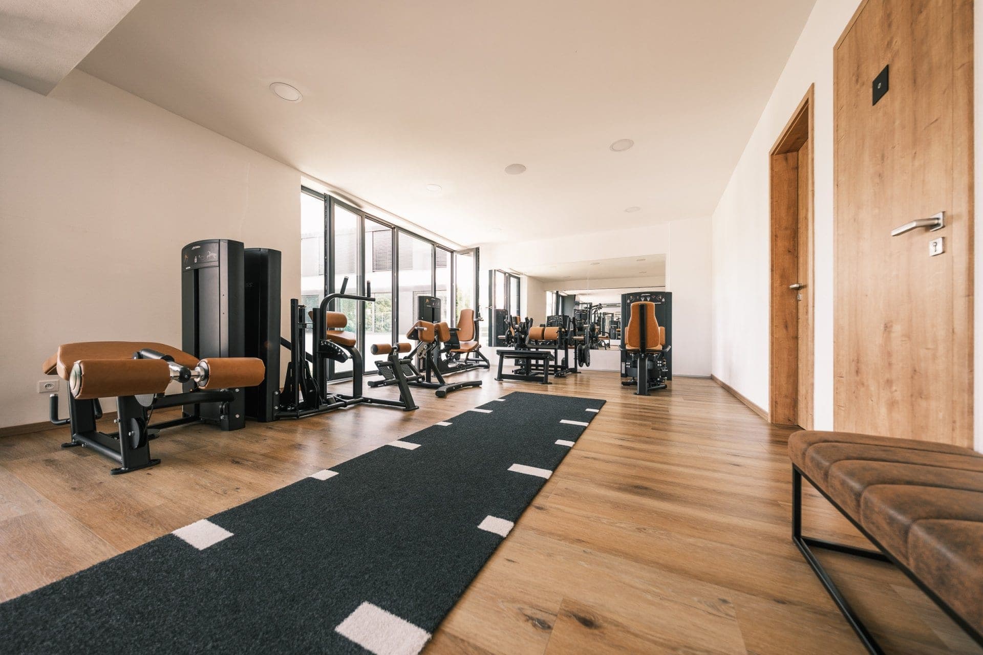 SKY FITNESS Praha: světlé patro s posilovacími stroji, dřevěnou podlahou a prosklenou stěnou